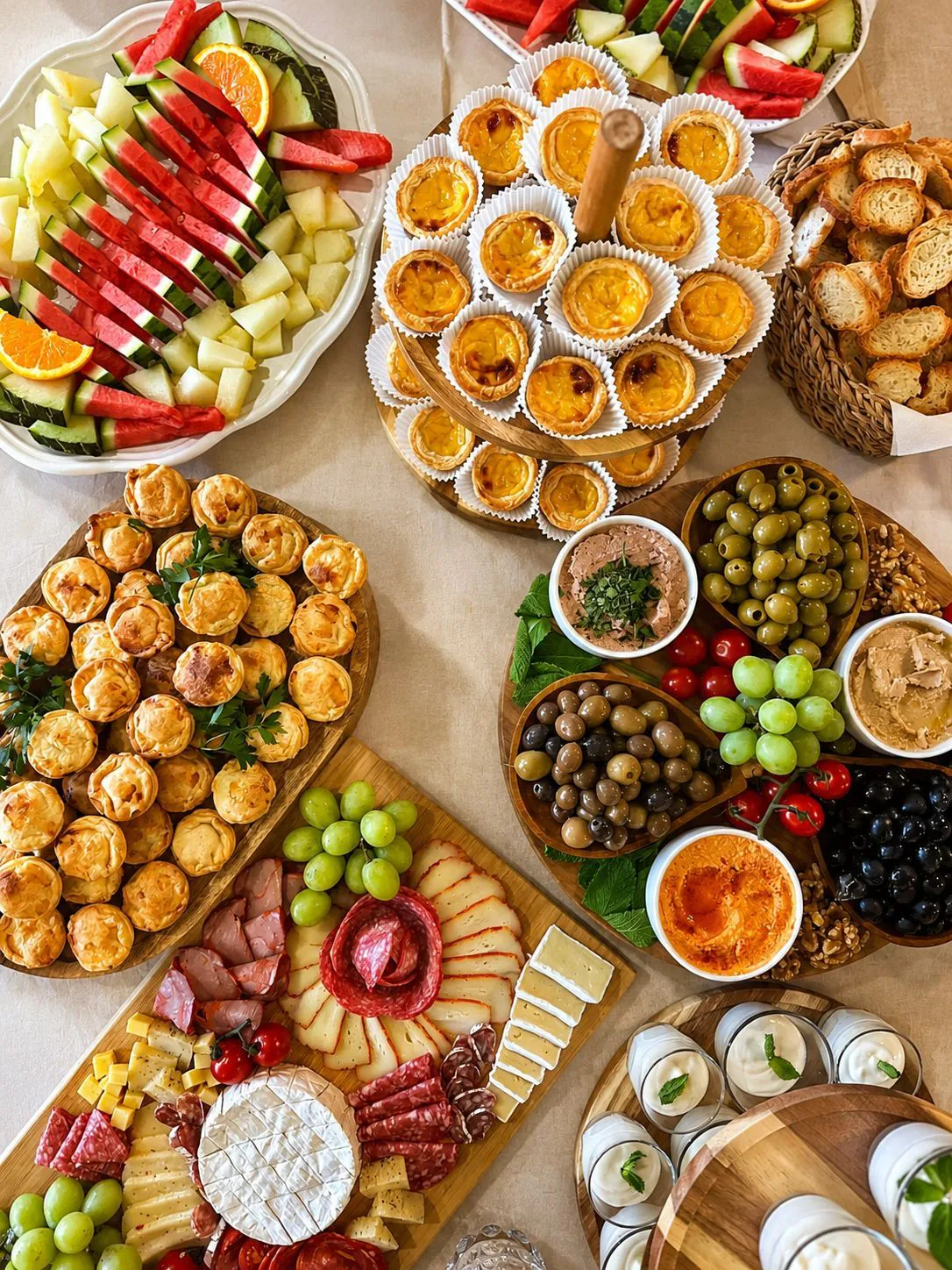 Mesa de celebração vista de cima com fruta, salgados, queijos e doces preparados para partilhar